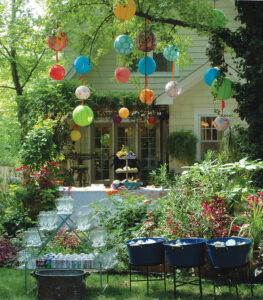 a highly decorated backyard with lush green landscaping and colorful hanging lanterns