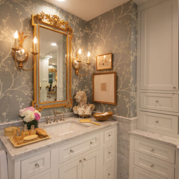 A marble top Kendall vanity and sink with gold bathroom decor and detailed gold mirror